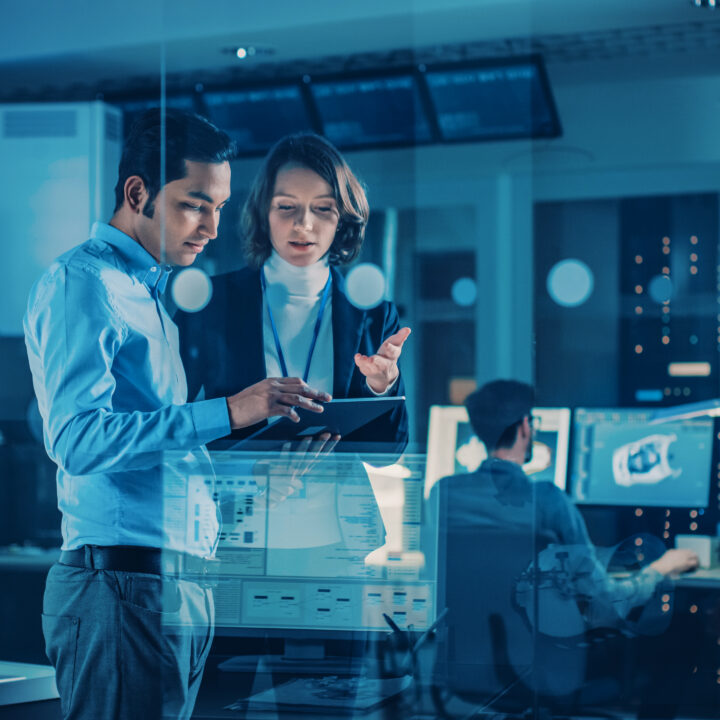 A group of six professionally dressed individuals, three men and three women, standing and smiling in front of a modern office building with large glass windows.