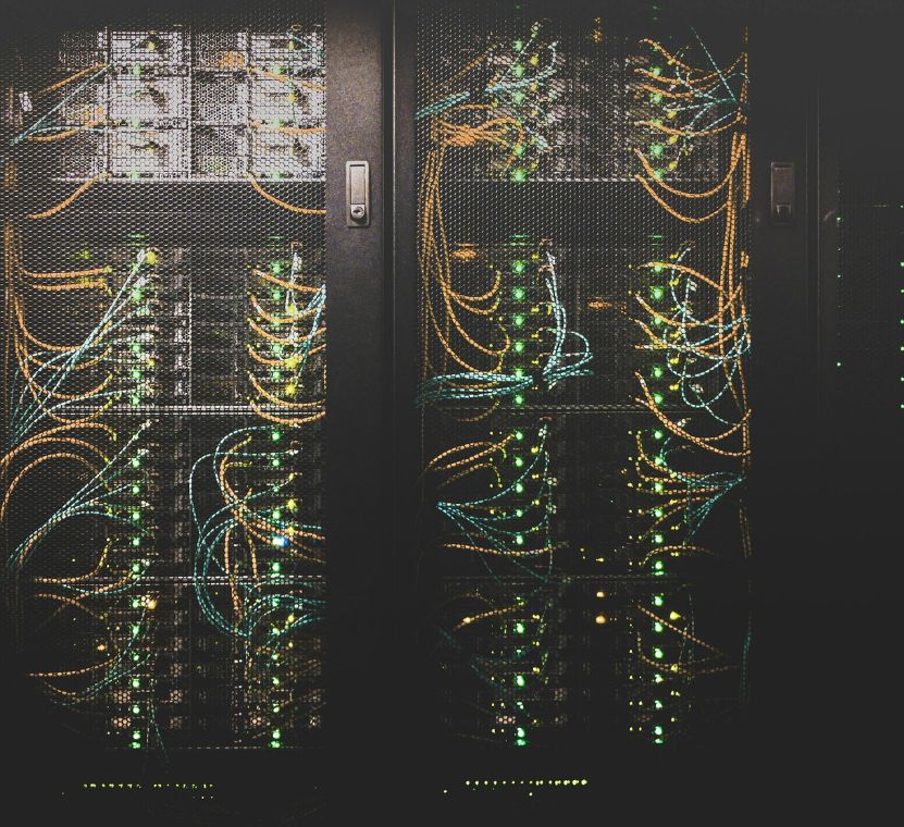 A modern data center with rows of server racks illuminated by blue and white LED lights, showcasing advanced networking equipment and cabling.